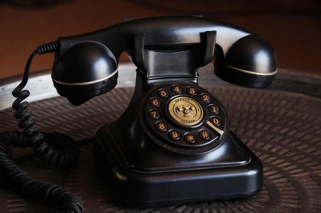 Close-up of a classic black vintage rotary dial telephone on a textured table.